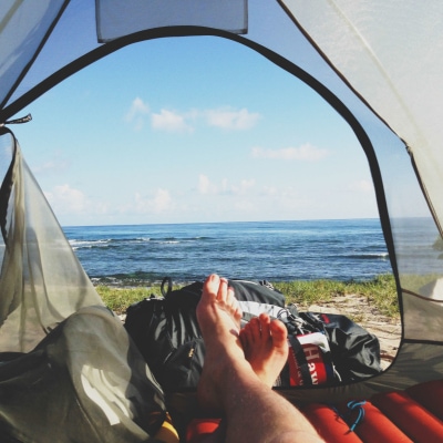 A person lying down in a tent watching the ocean