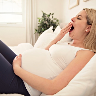 tired pregnant woman yawning, she is dealing with fatigue in pregnancy