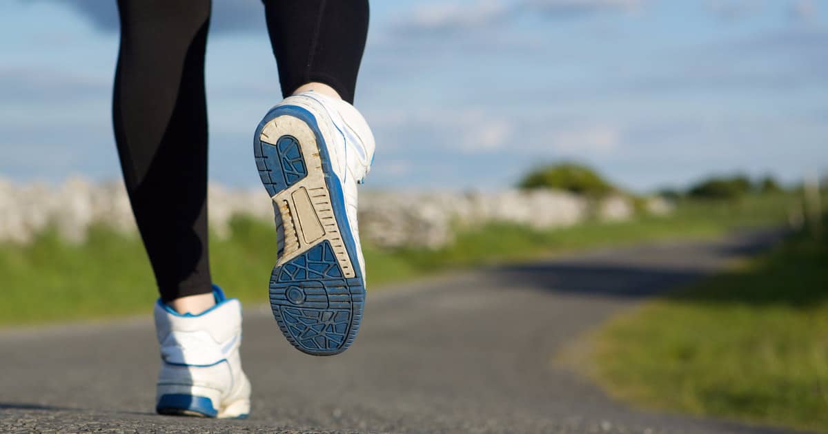 A woman running in white blue sneakers on road