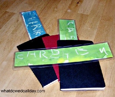Three plain-cover books (two black and one red) with three child-made bookmarks (two green and one blue)
