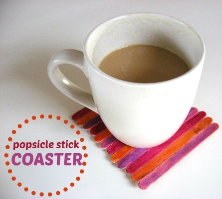 A white mug with tea in it on top of a coaster made from popsicle sticks colored with orange and pink marker. The text on the image says 