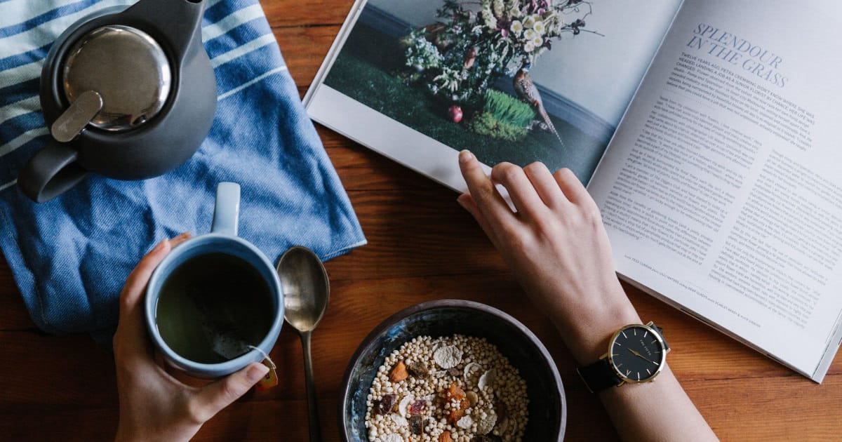 A person viewing a magazine while having breakfast