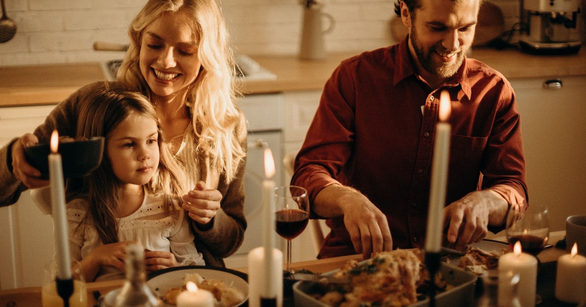 laughing couple at candlelit dinner with daughter on lap