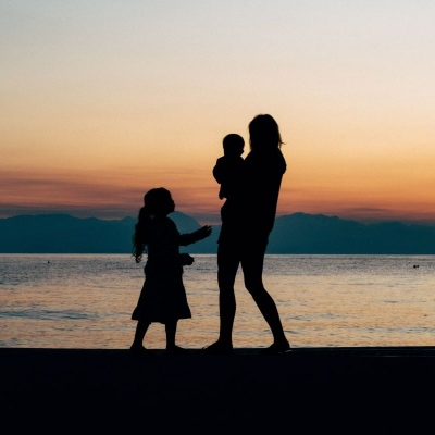 A silhouette of a lady with a baby and a young lady