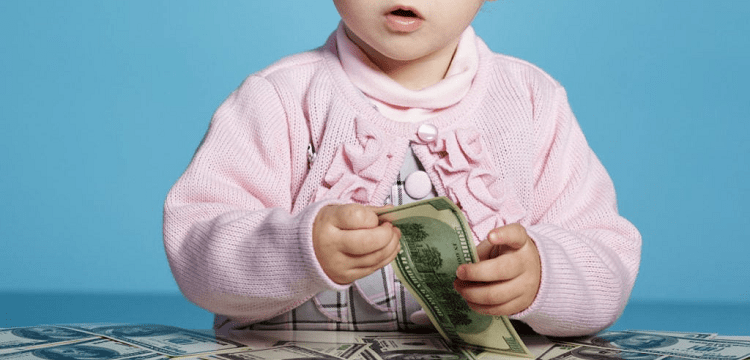baby wearing pink sweater holding money