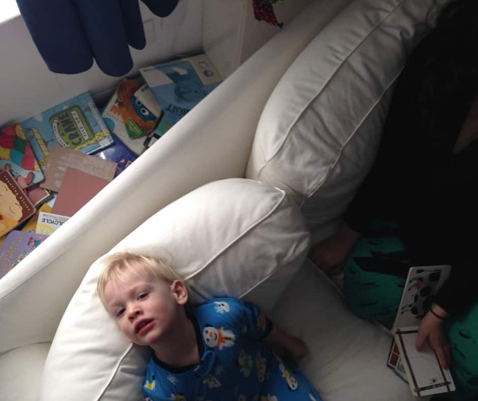 A child seated on a couch while looking up to the ceiling