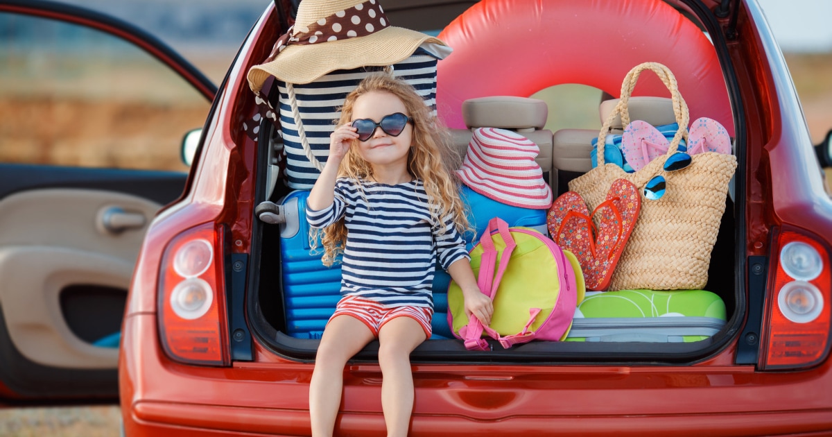 little girl sitting in open trunk with tons of beach gear inside