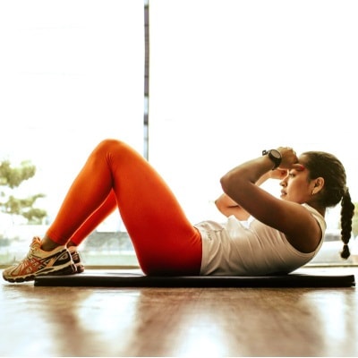woman does sit up; she wears orange leggings and has a braided ponytail