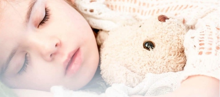 child asleep with a teddy
