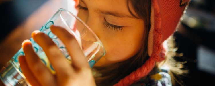 A little girl drinking water from a glass