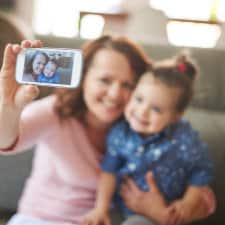 A woman holding a baby and taking selfies