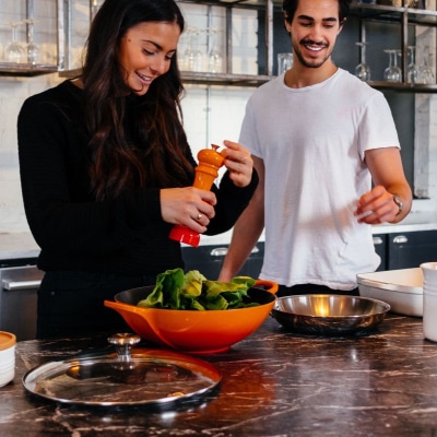 man and woman cook food in an orange wok