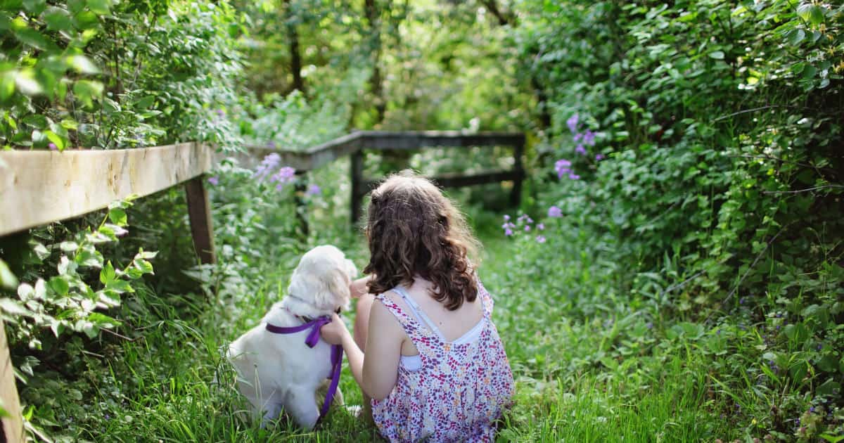 A little girl with her puppy sitting in a garden