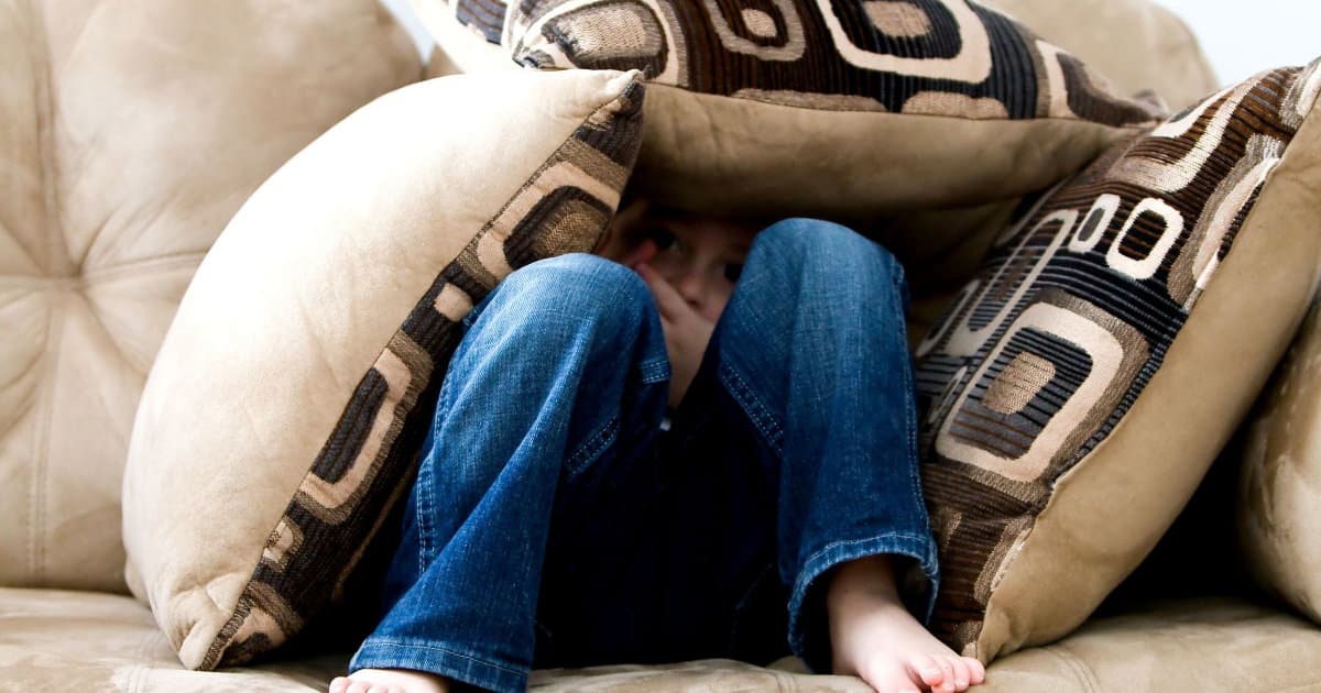 A kid holed up under pillows