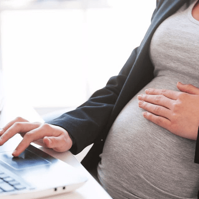 A pregnant woman using a laptop.