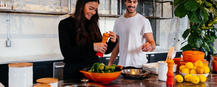 man and woman cook dinner together with orange cookware