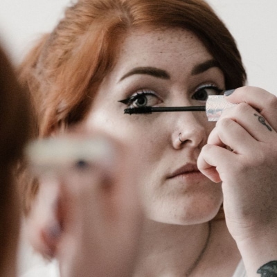 A woman applying mascara on her eyelashes