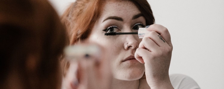 A woman applying mascara on her eyelashes