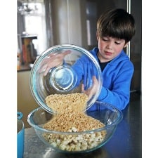 A child mixing popcorn on a transparent bowl