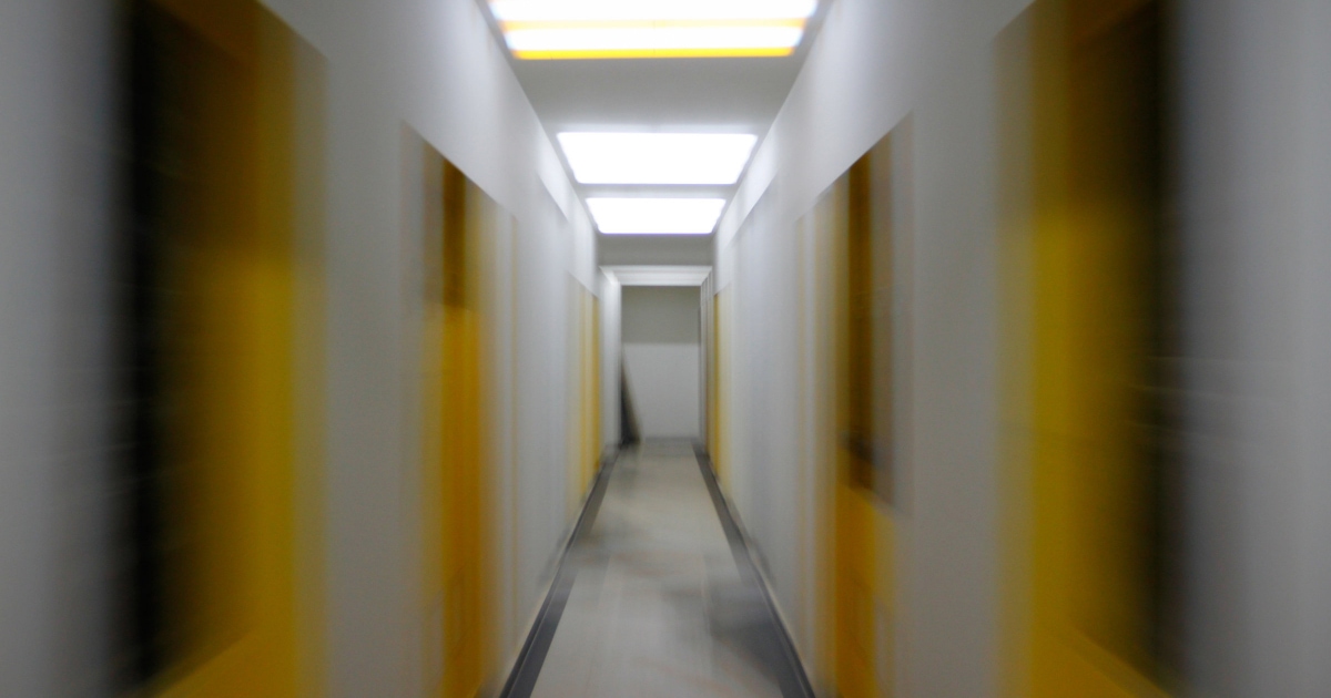 white hallway with yellow doors, photograph is blurred as if you're in motion