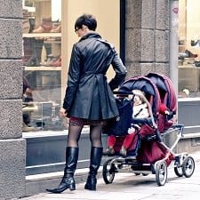 A woman holding her baby in a stroller.