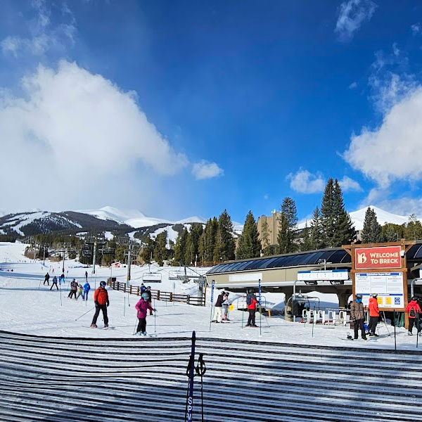 Breckenridge Ski Resort in Colorado -- a blue sky, mountains, skiers, and evergreen trees