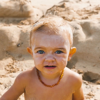 A young boy sitting on a sandy beach