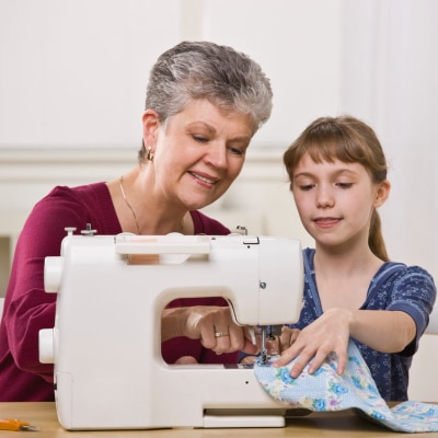 A lady teaching a kids to sew