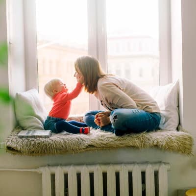 A woman playing with a baby on a cot