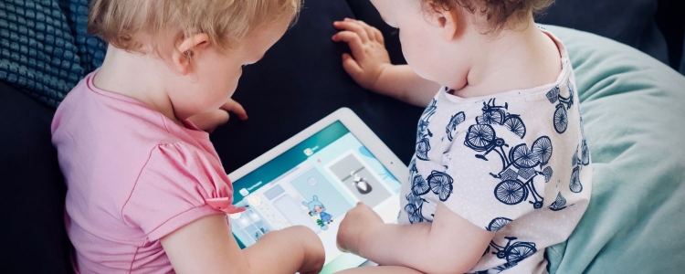 2 toddlers play on an iPad