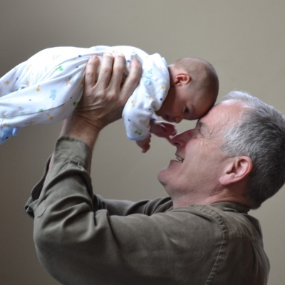 A Grandparent holding a baby in the air