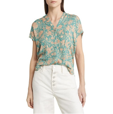 woman wears green floral top with white pants