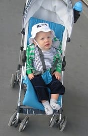 A child wearing summer outfit in a blue stroller