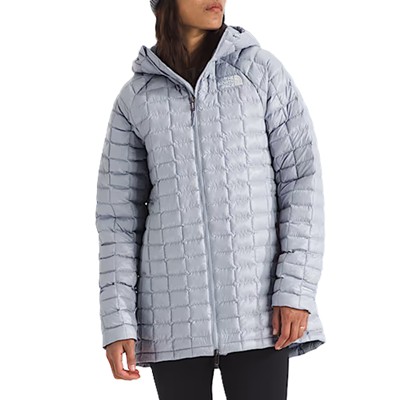 A woman wearing a gray winter coat, gray winter hat, and black leggings
