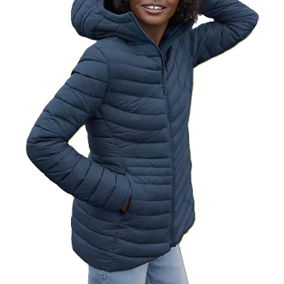 A woman wearing a dark blue hooded winter coat and blue jeans