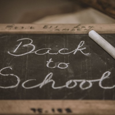 black chalkboard says "Back to School" written in cursive with white chalk
