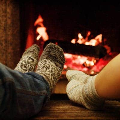 Two persons warming their toes by the fireplace