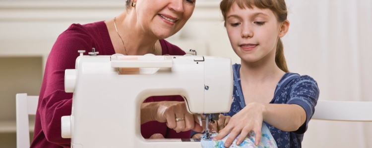 grandmother teaching a 10-year-old girl how to sew on a sewing machine