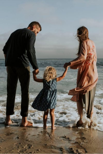 A man, a woman and a child standing at the beach