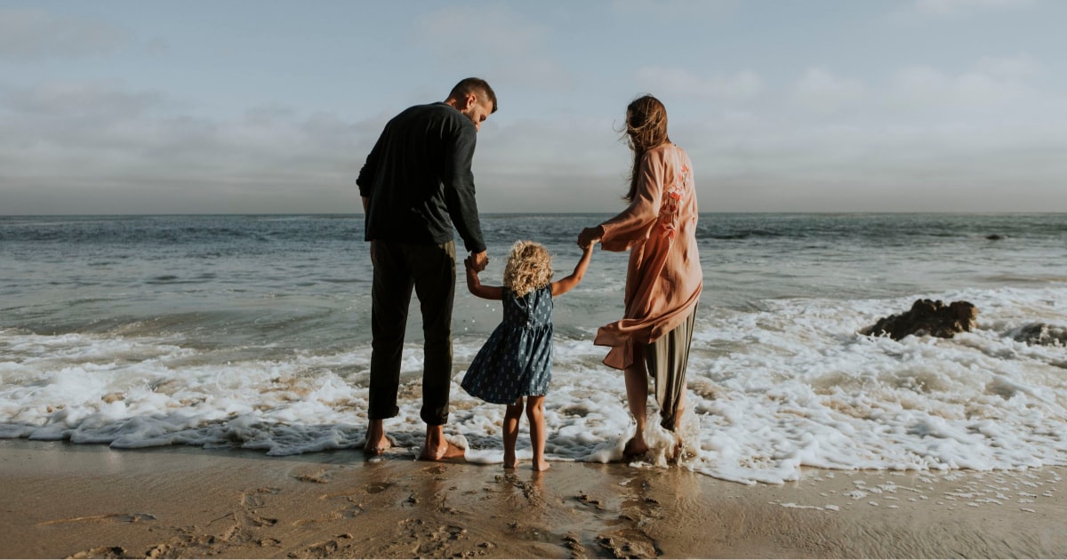 A man, a woman and a child standing at the beach