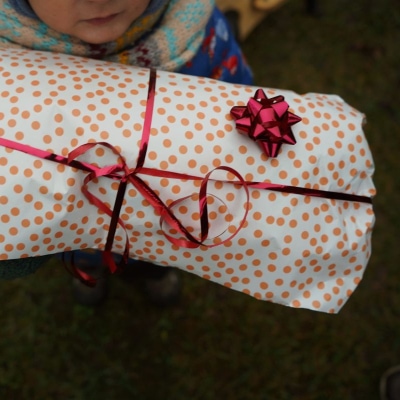 a child (face mostly cropped out) holding a wrapped gift